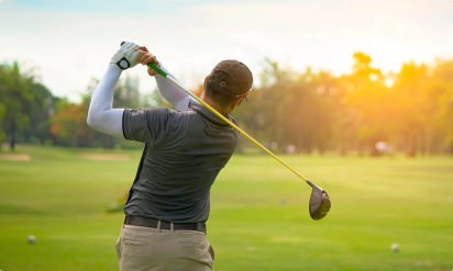 Rear view of Golfer playing his shot in the field 