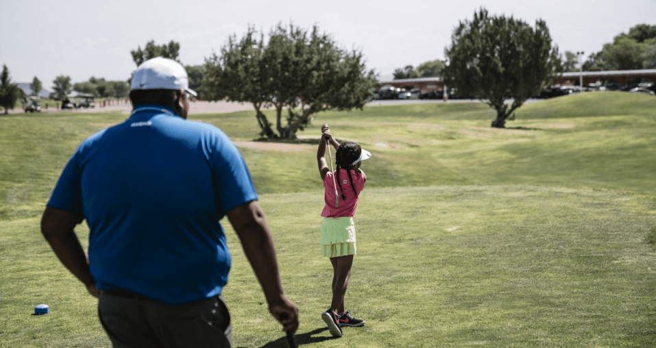  One golfer plays a shot while the other looks on