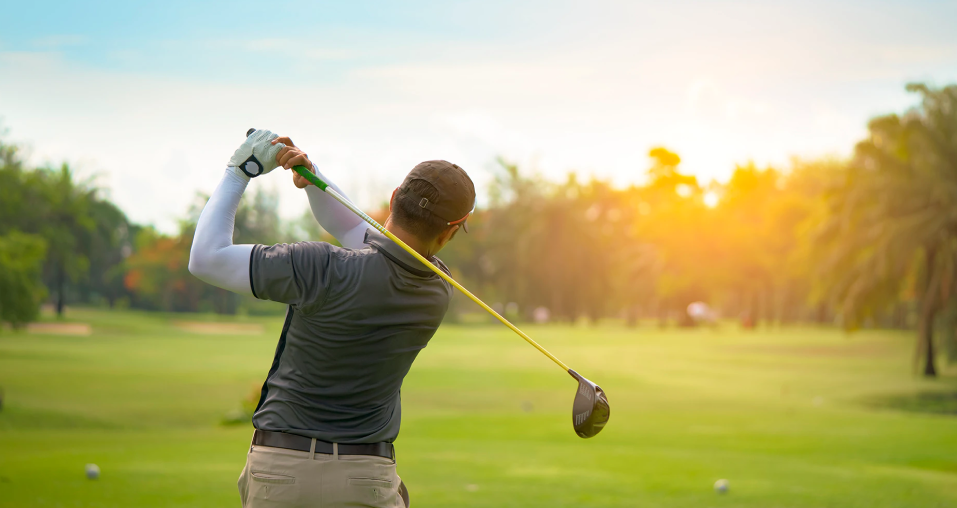 Rear view of Golfer playing his shot in the field