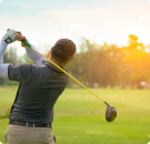 Rear view of Golfer playing his shot in the field 